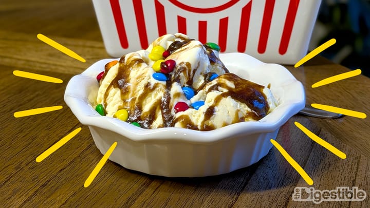 An ice cream sundae in front of a popcorn bucket.